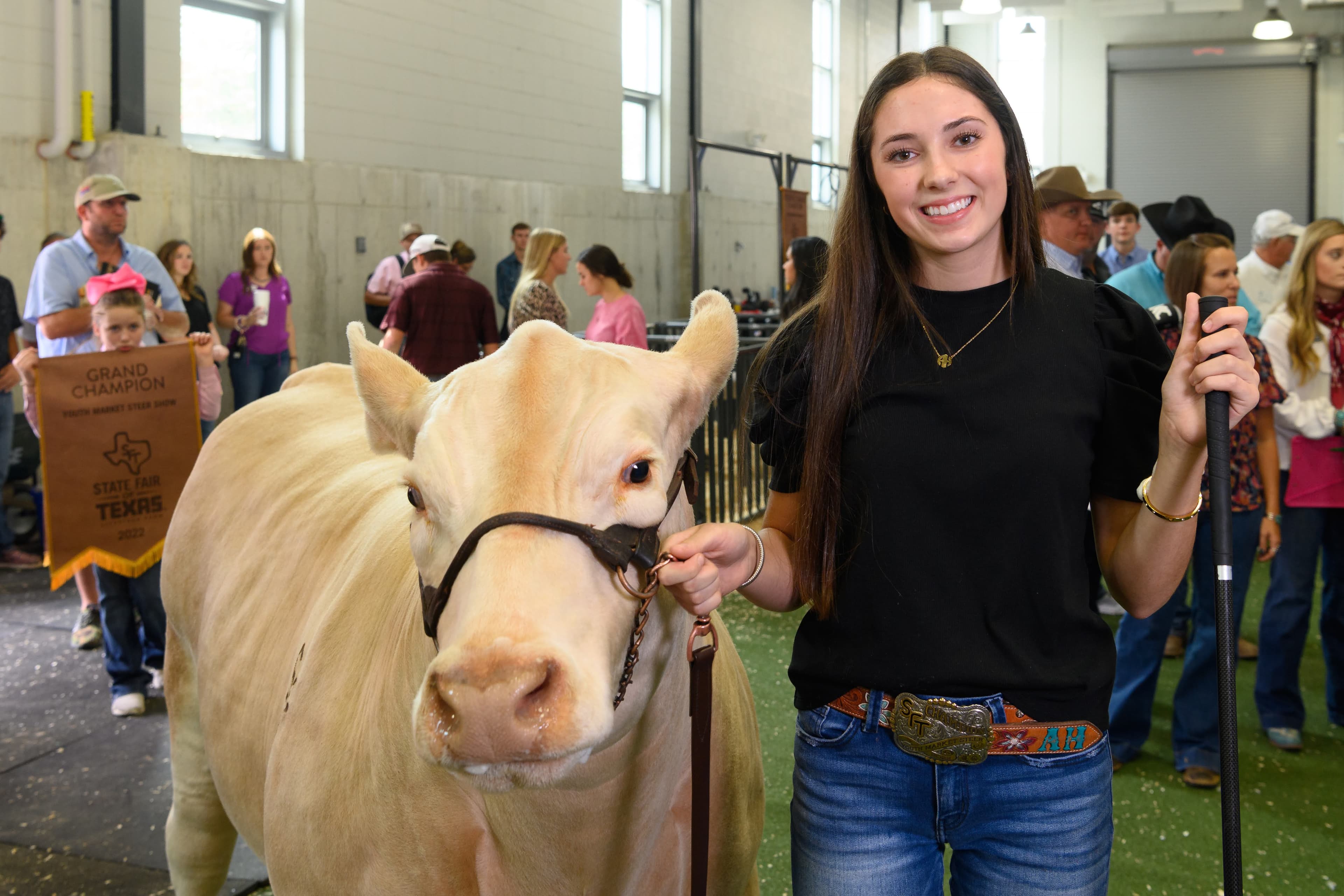 File photo: A woman stands beside a light-colored animal at an indoor fair display.